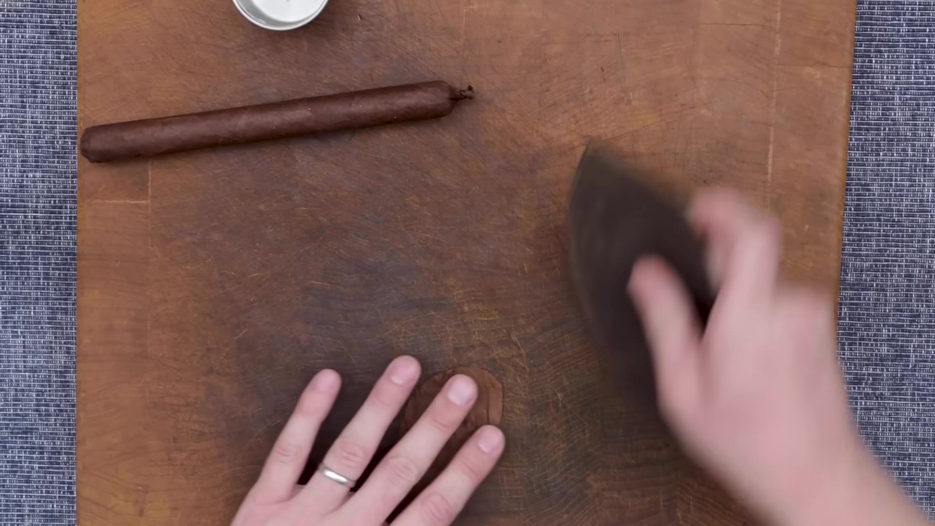 A completed straight hand-rolled cigar resting on the wooden board